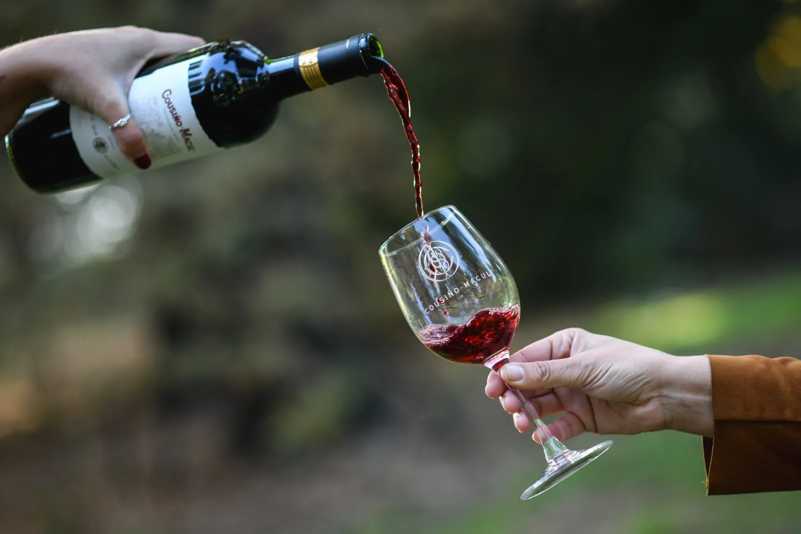 Red wine poured from a Cousiño Macul bottle into an engraved tasting glass