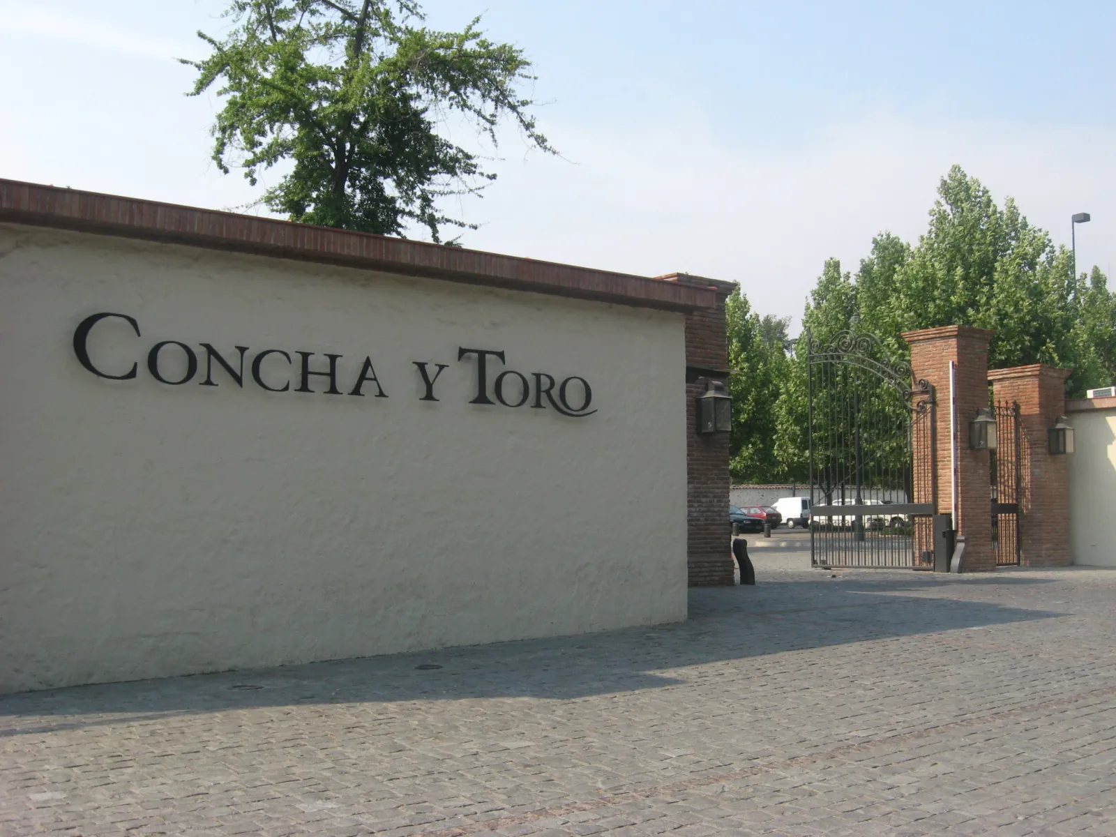 Concha y Toro lettering on a cream wall beside a brick-pillared iron gate