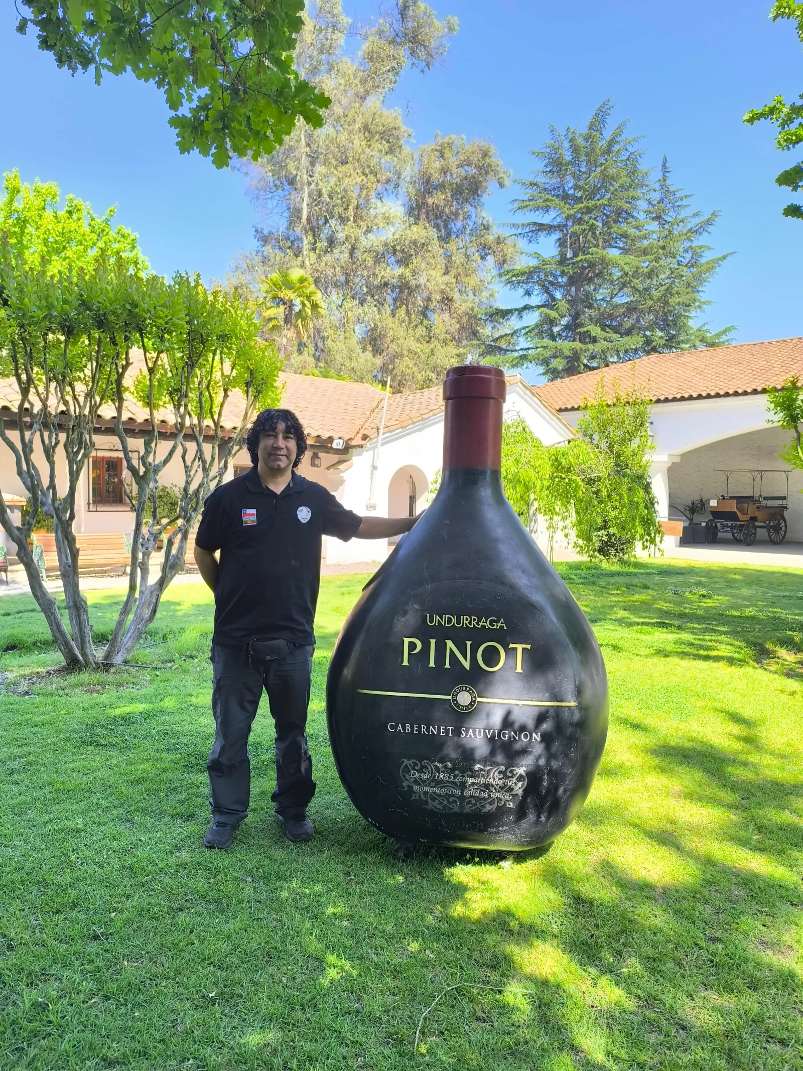 Man standing beside a giant Undurraga Pinot bottle on the lawn