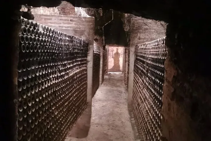 Narrow underground passage stacked with dusty bottles on both sides