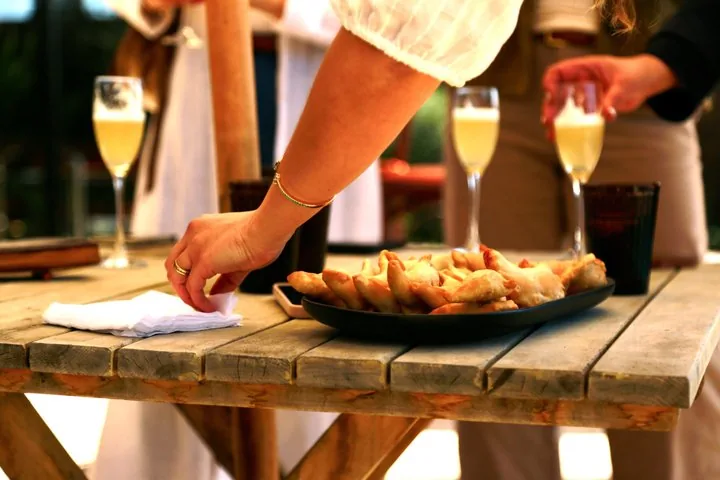 Plate of golden empanadas on a rustic table with glasses of sparkling drinks