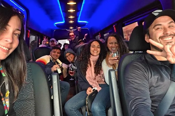 Smiling tour group seated inside a minivan with blue ceiling lights