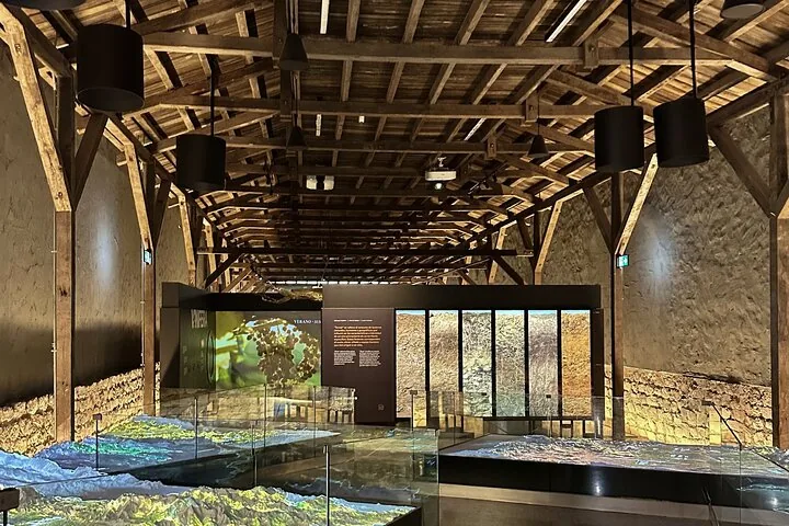 Timber-roofed exhibition hall with an illuminated relief map of valleys