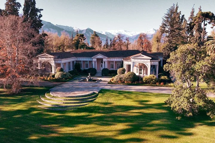 Historic manor house with gardens and lawns below snowy mountains