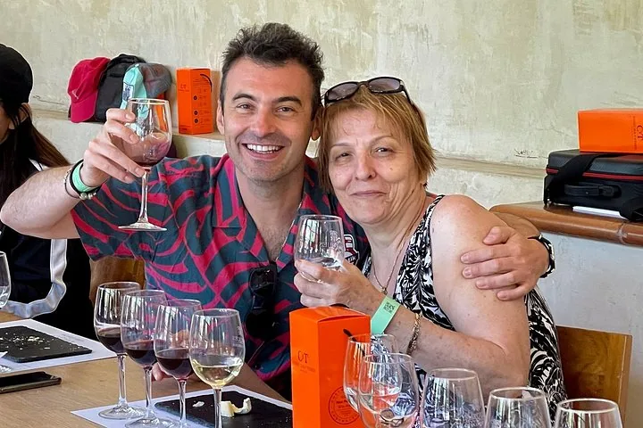 Two visitors raising glasses behind a row of tasting glasses