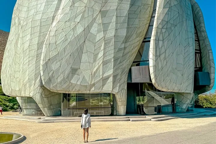 Visitor standing before the curved marble-clad petals of the temple