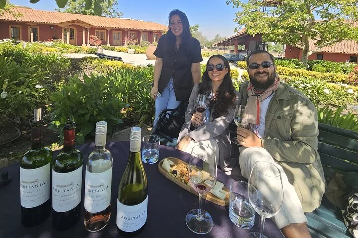 Couple tasting Aquitania wines at a garden table with a cheese board
